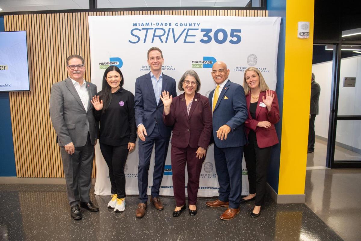 6 men and women standing in front of a sign that says "Strive 305"