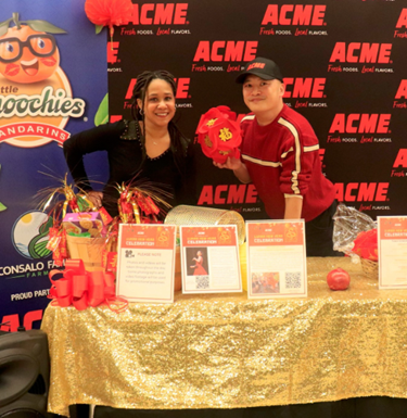 People posing at booth with "ACME" logo