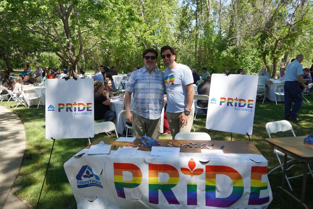 Two people posing at booth that says "PRIDE"
