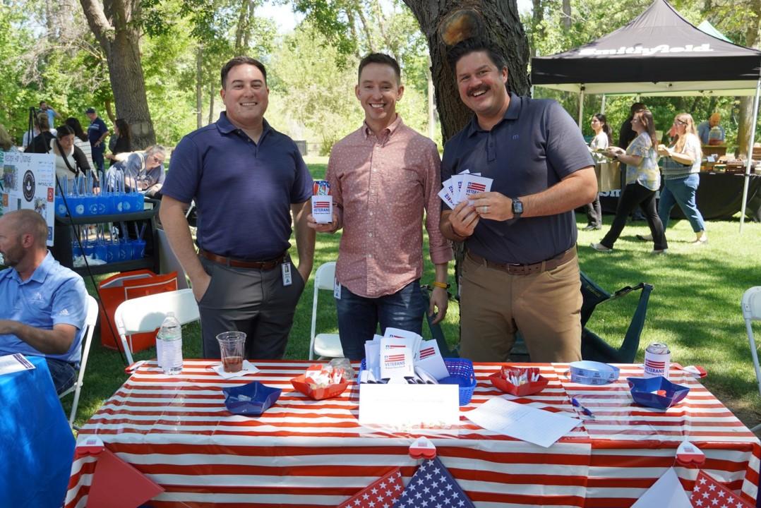 Three people posing at booth with American flags