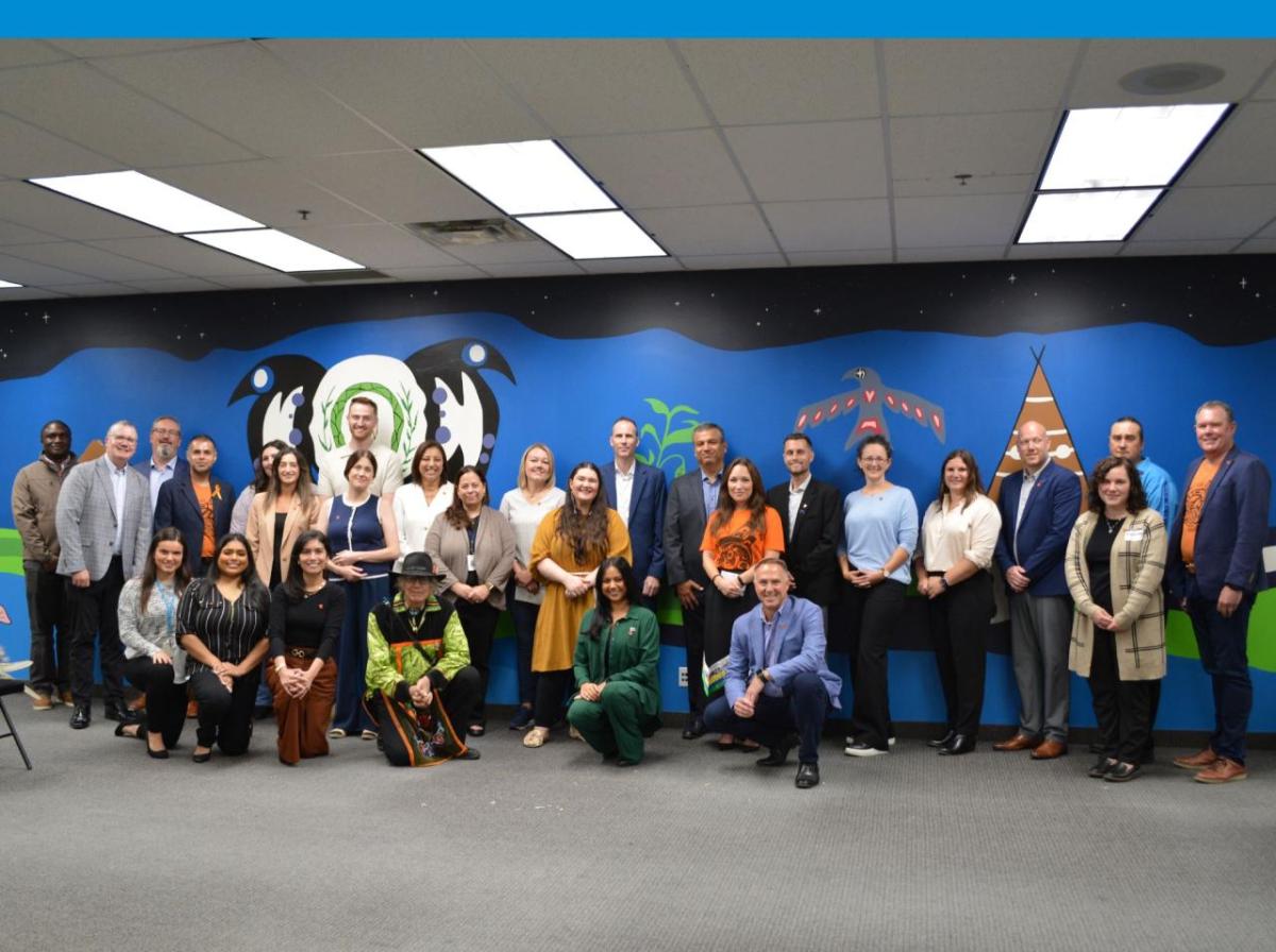 A group of people posing in front of a large mural