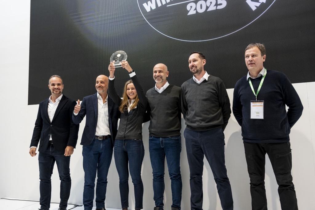 Six people posing together, one holding up an award