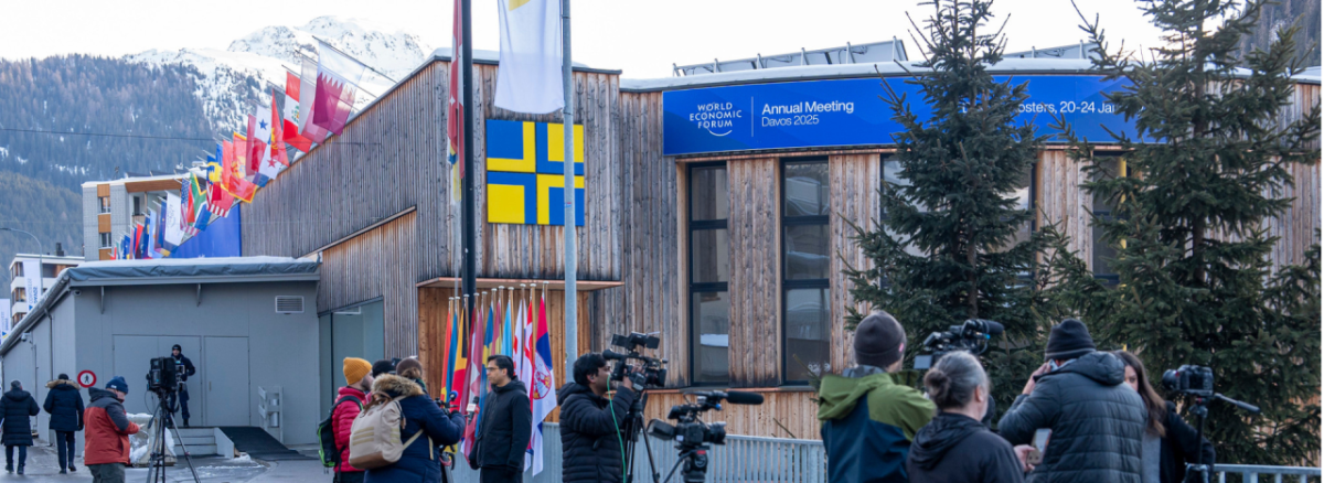 A building with Alps in the background, and people gathering outside