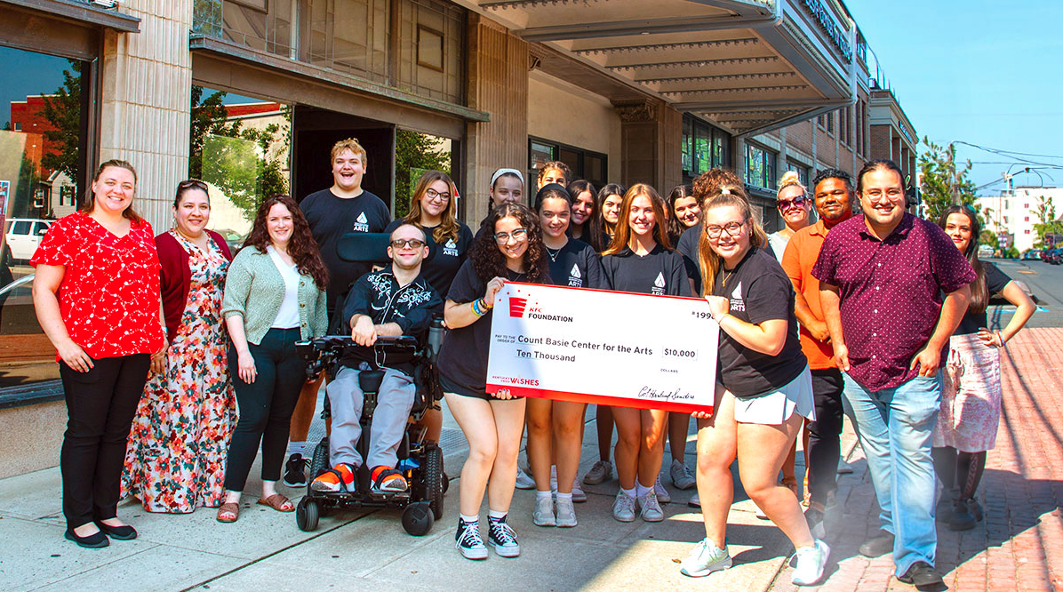 A group of people posing and smiling with an oversized check