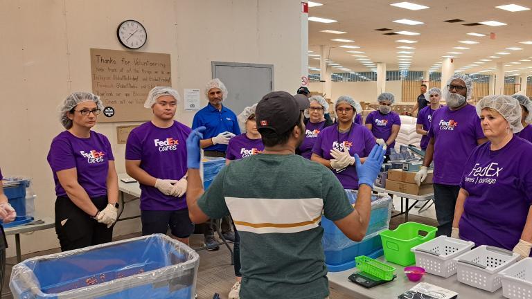 People in FedEx t-shirts and hair nets listening to someone