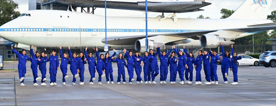 She Is an Astronaut participants in a line in front of a Nasa airplane