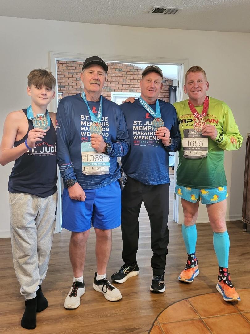 Four people posing together with medals around their necks