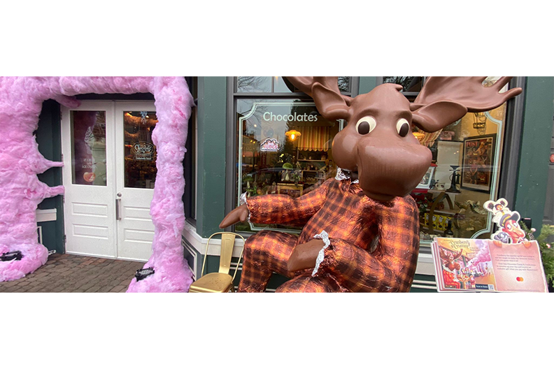 A giant chocolate moose "sitting" in front of a store