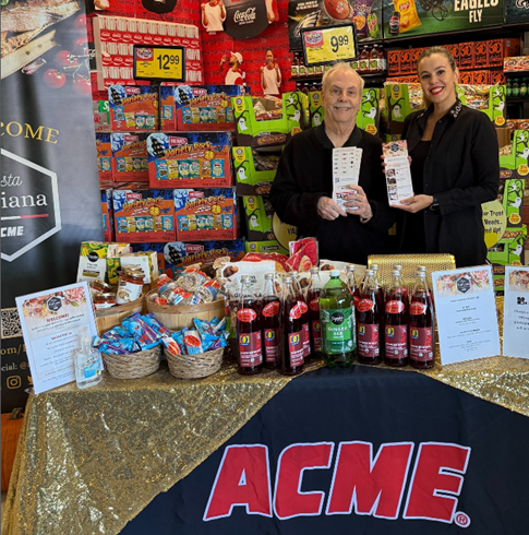 A person and person standing next to a table with food items