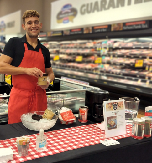 A person standing behind a table with food items