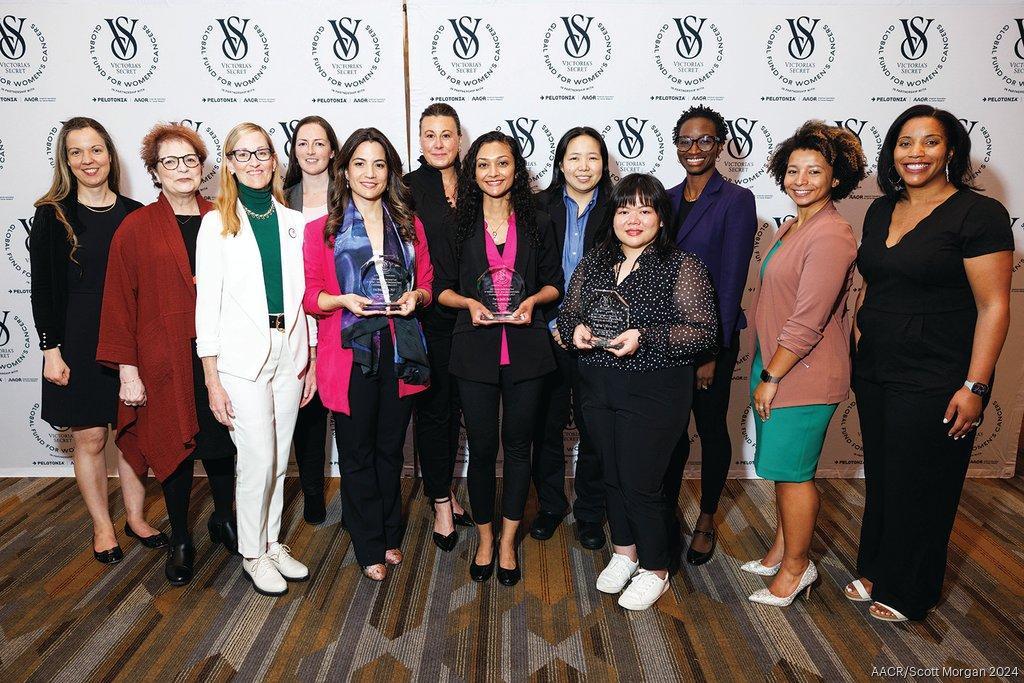 A group of women, 3 holding glass awards, in front of a VS Global Fund for Women's Cancer backdrop