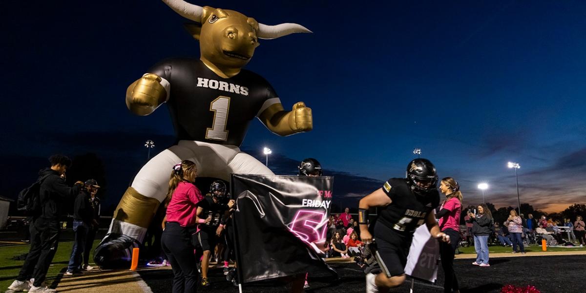 Football players run through banner