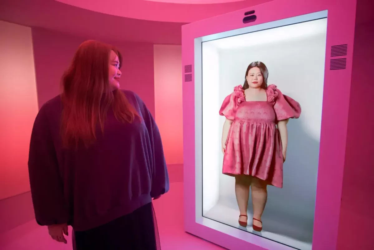 A person stood in front of a screen displaying an AI avatar 