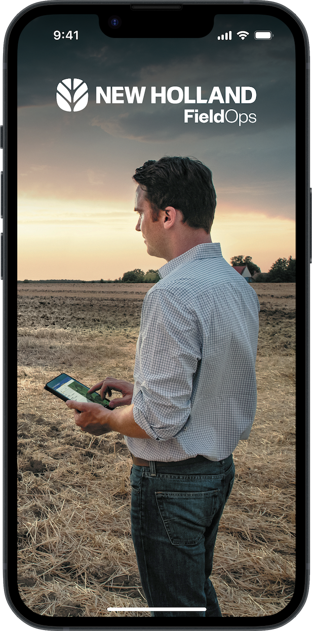 A mobile phone with a photo on the screen on a person stood in a field holding a tablet PC