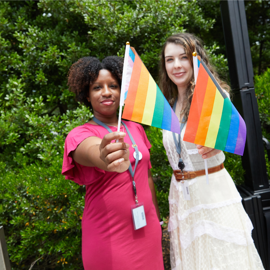 Two women holding Pride Flags outside during Pride Flag raising