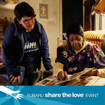 A Meals on Wheels worker looks on as a senior shows pictures in an album