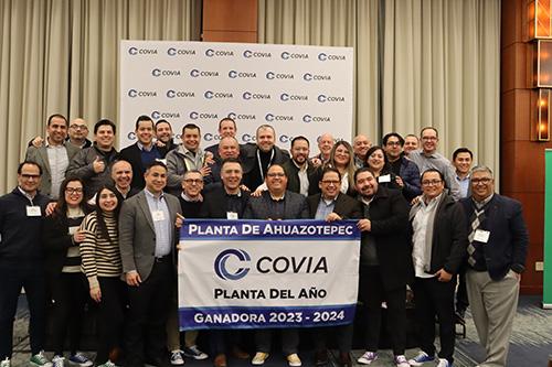 A group of people posed behind a Covia banner