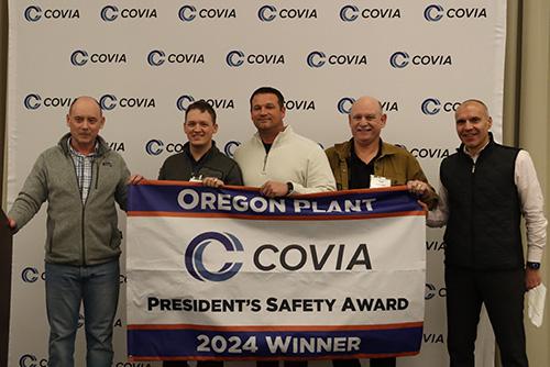 Five people smiling behind a Covia banner