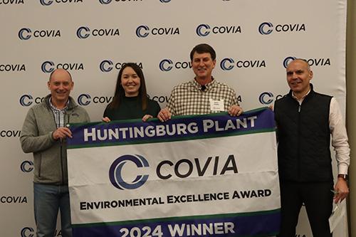 Four people smiling behind a Covia banner