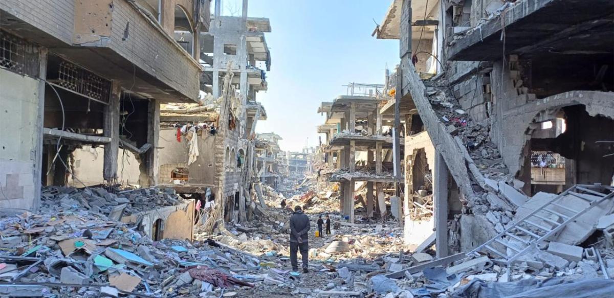 Man walks through street lined with destroyed buildings