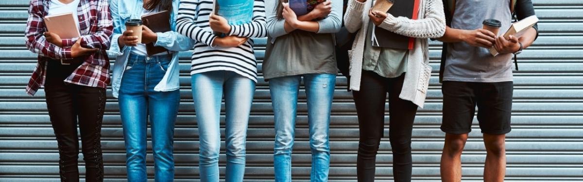 legs and bodies of people wearing jeans, t-shirts, sweaters and shorts, holding phones and coffee cups