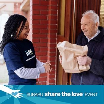 A Meals on Wheels worker delivers a meal to a smiling recipient