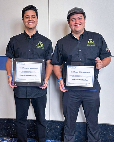 Two people standing together holding certificates