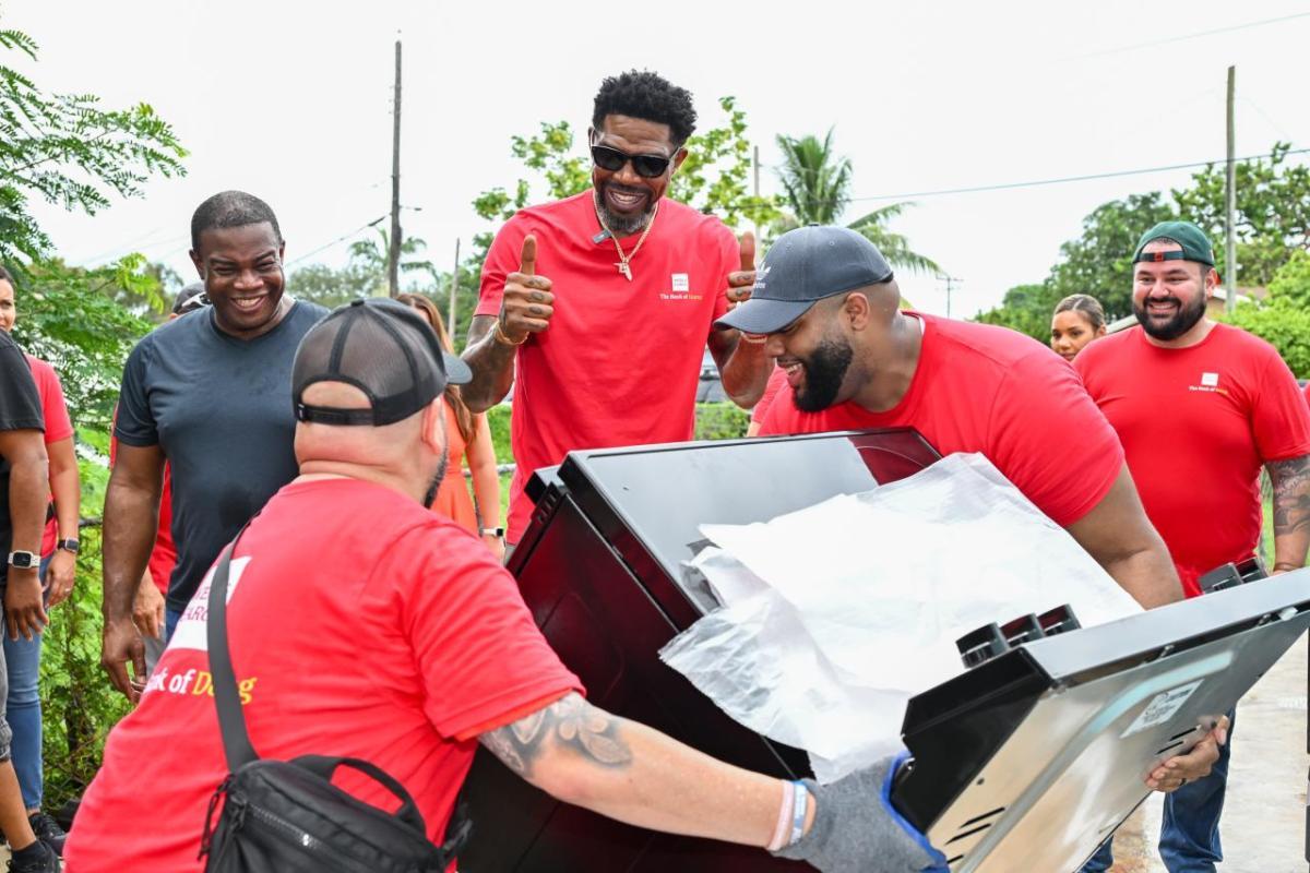 Volunteers in red shirts carrying a new oven