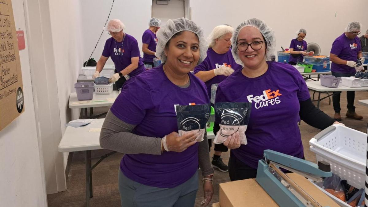 Two smiling people in FedEx Cares t-shirts and hairnets