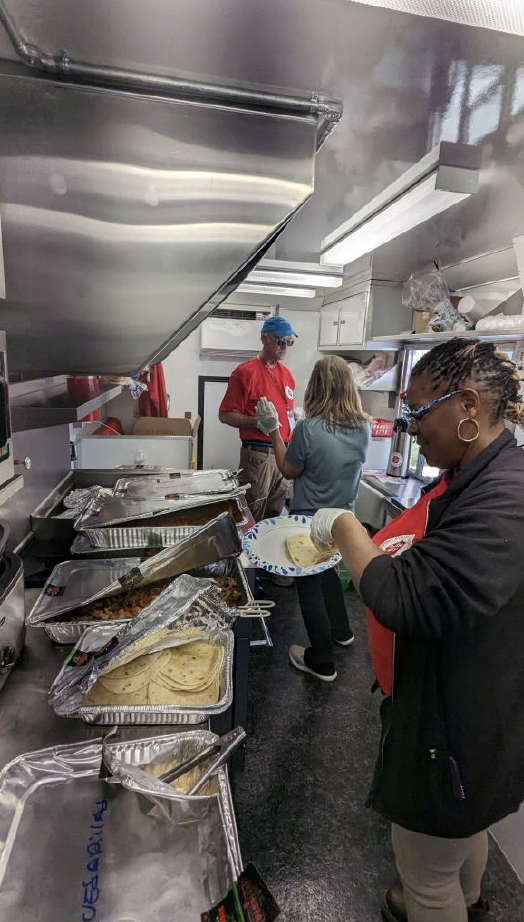 People serving food in the back of  the FedEx canteen truck