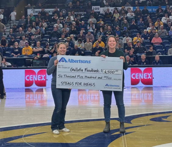 Two people holding a check on a basketball court