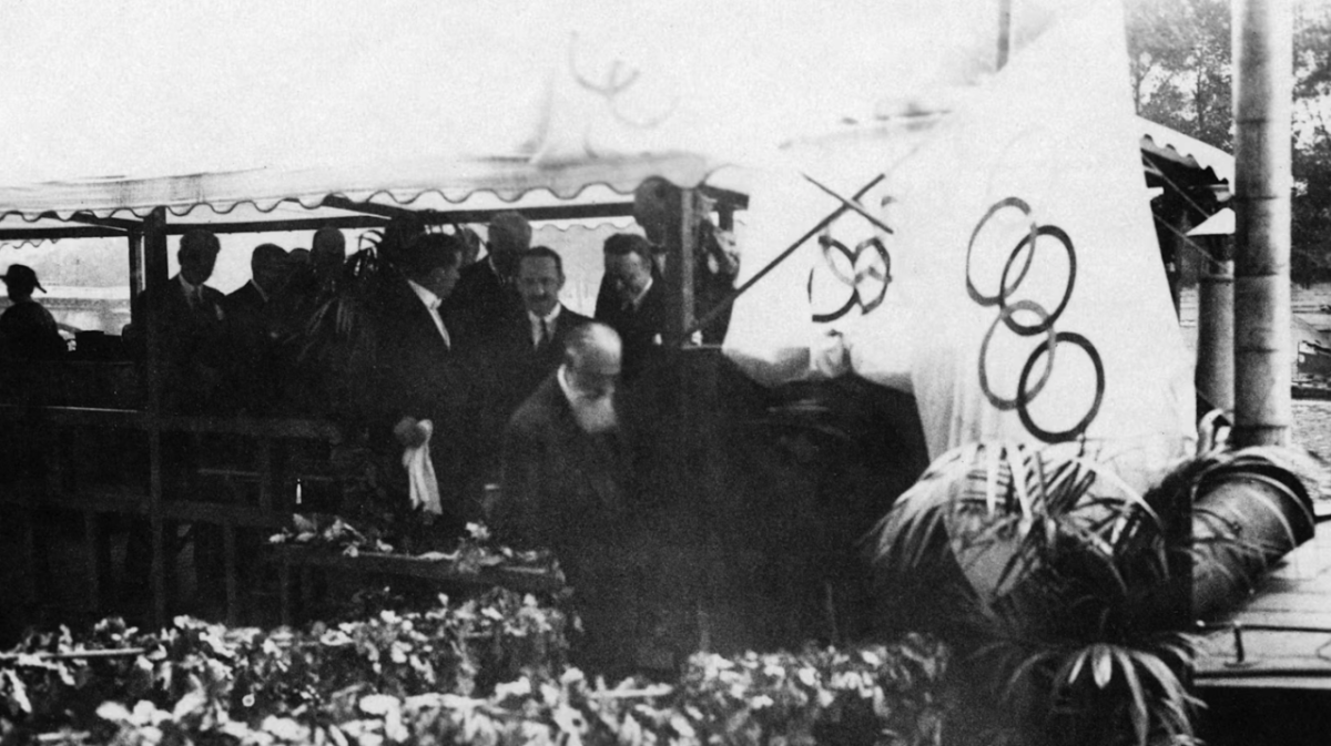 People under a tent near Olympic flags in 1924