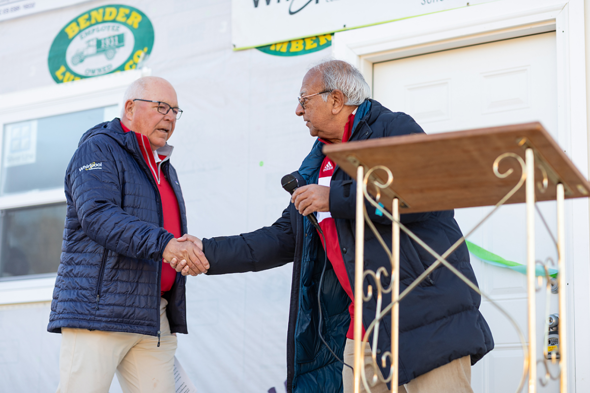 Two people shaking hands behind a podium