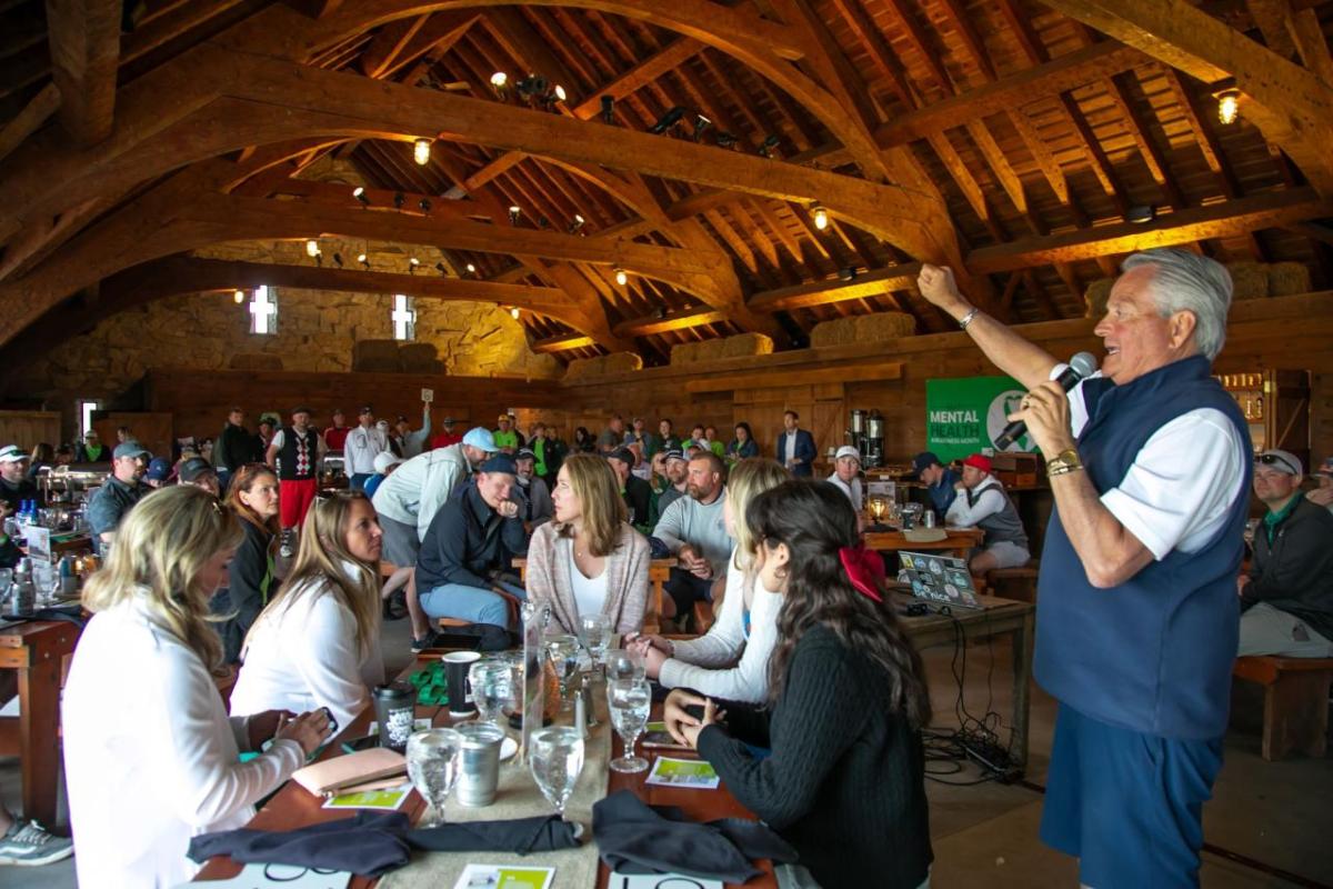 A person giving a speech to others during a meal inside a wooden building