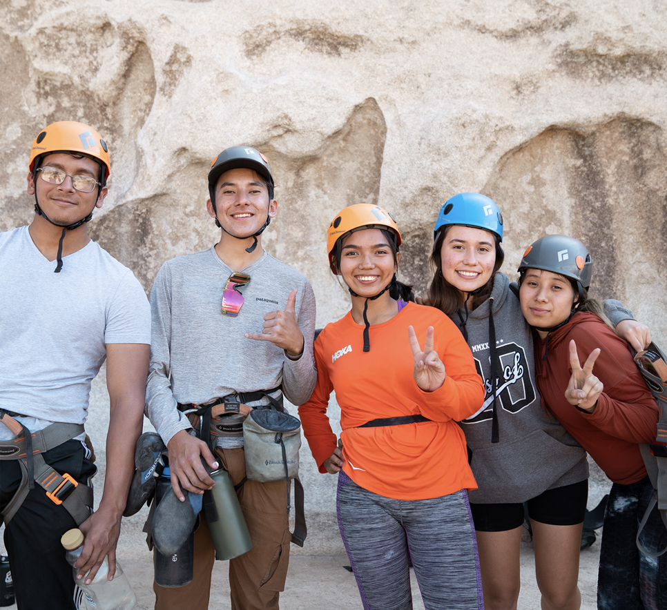 Young people in climbing gear standing and smiling together