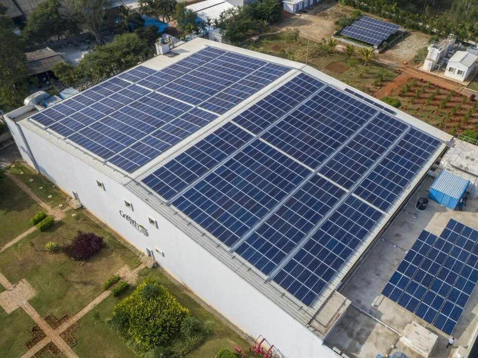 Aerial view of a large building, the roof covered with solar panels.