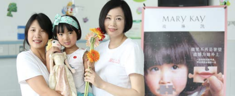 On the left, Wendy Wang, President of Mary Kay Asia Pacific region holding a young child whilst stood next to another person holding flowers