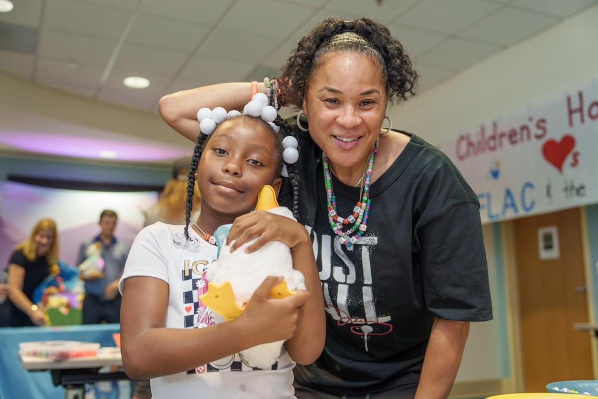 Aflac Coach Dawn Staley shown with a young female patient holding an Aflac My Special Duck.