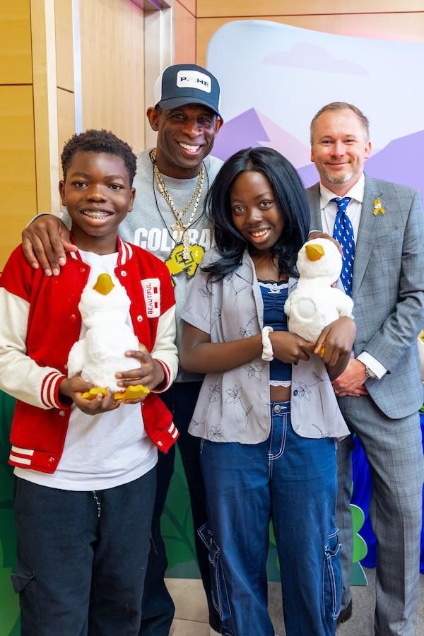Deion Sanders shown with young patients holding the Aflac Duck.