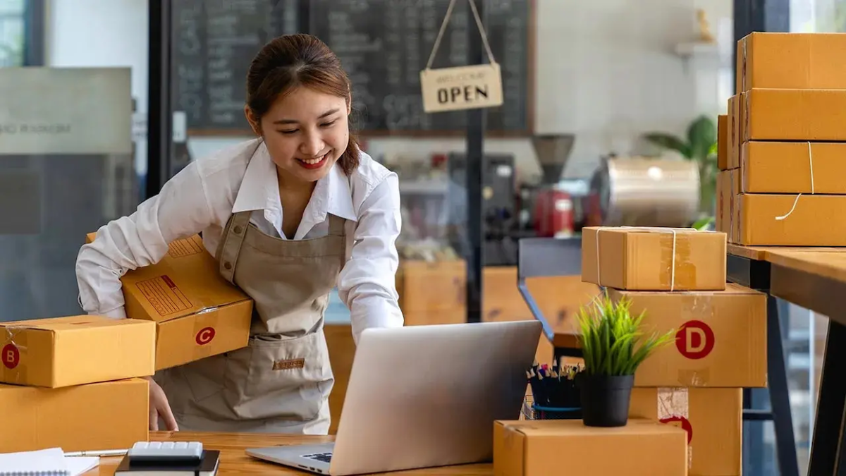 Female business owner packing boxes for shipping.