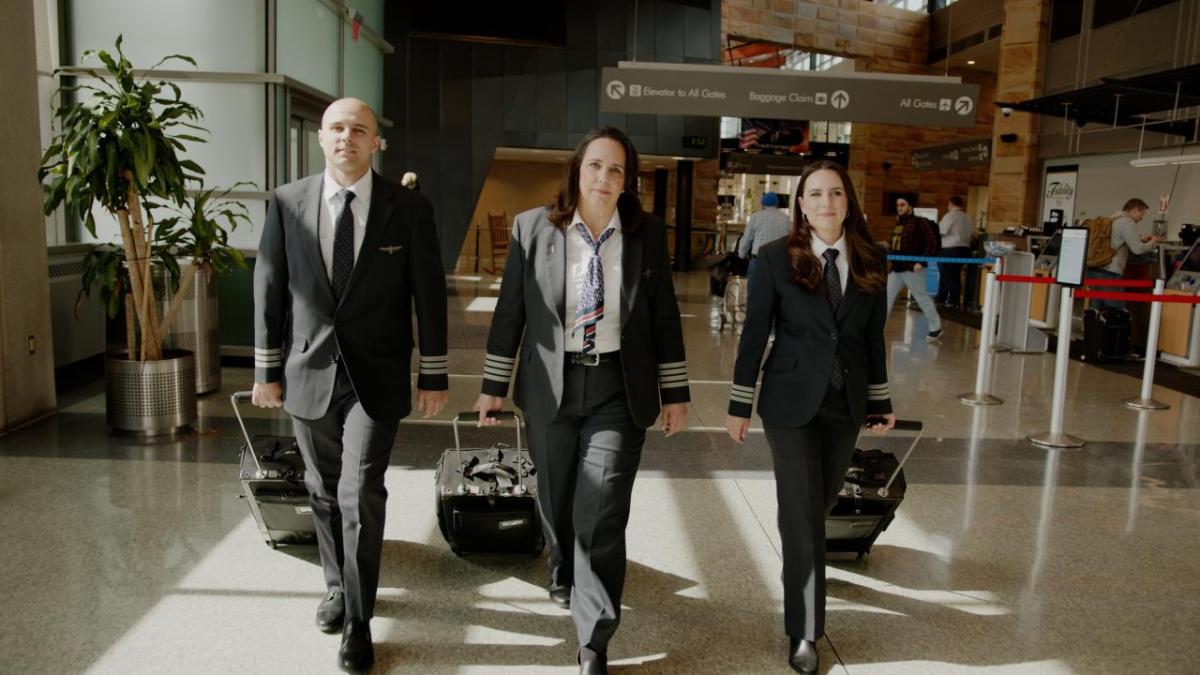 Three pilots walking through an airport with their suitcases 