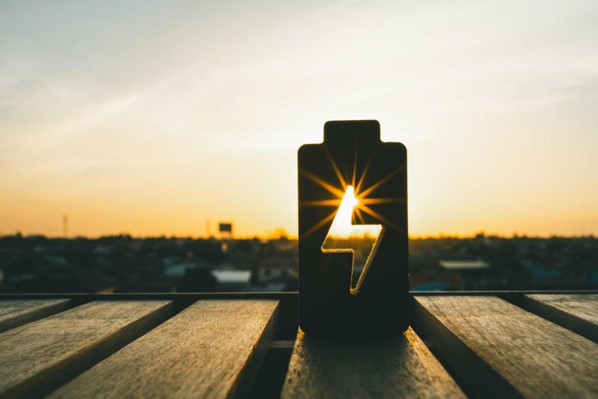 A cut out of a battery symbol on a table, showing the sunsetting in the gap