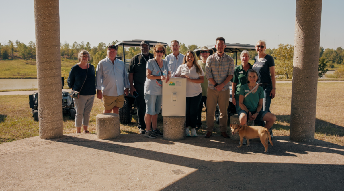 Group of people and a dog stand around in sunny area with oversized prop light switch.