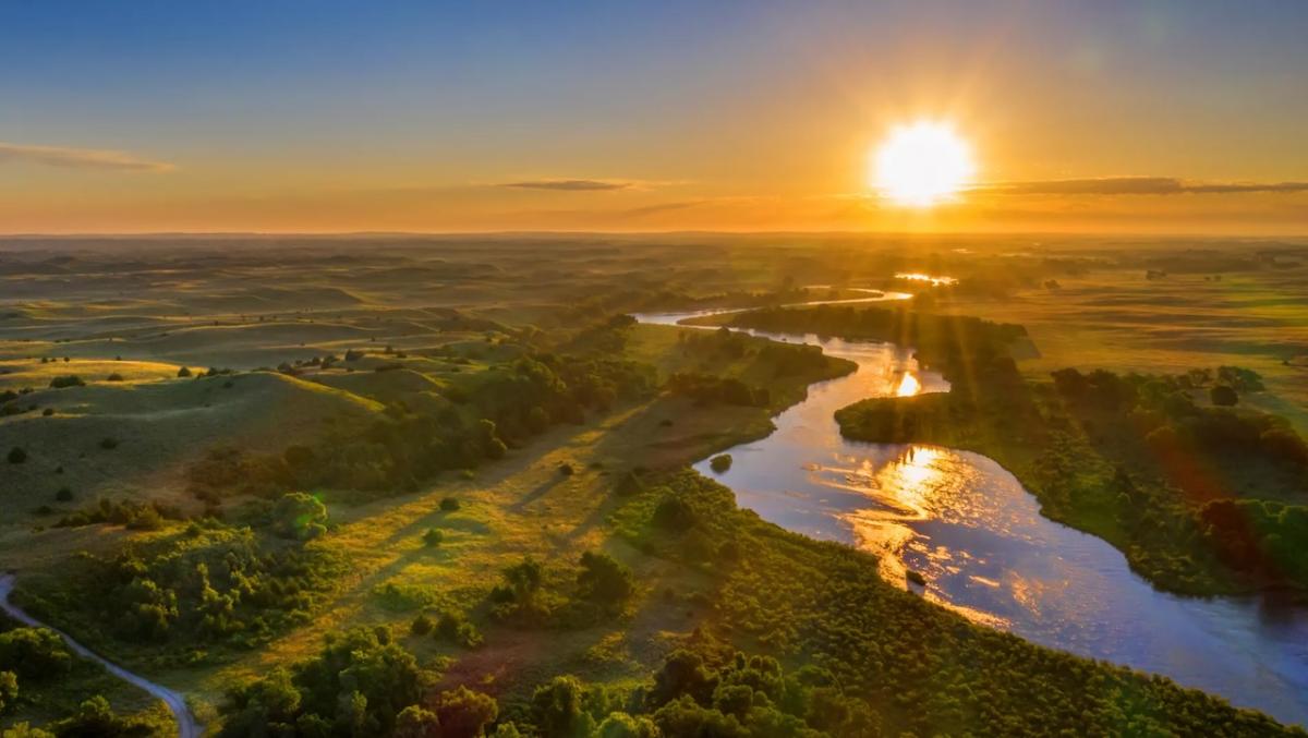 Sunset shown over a river and a valley.