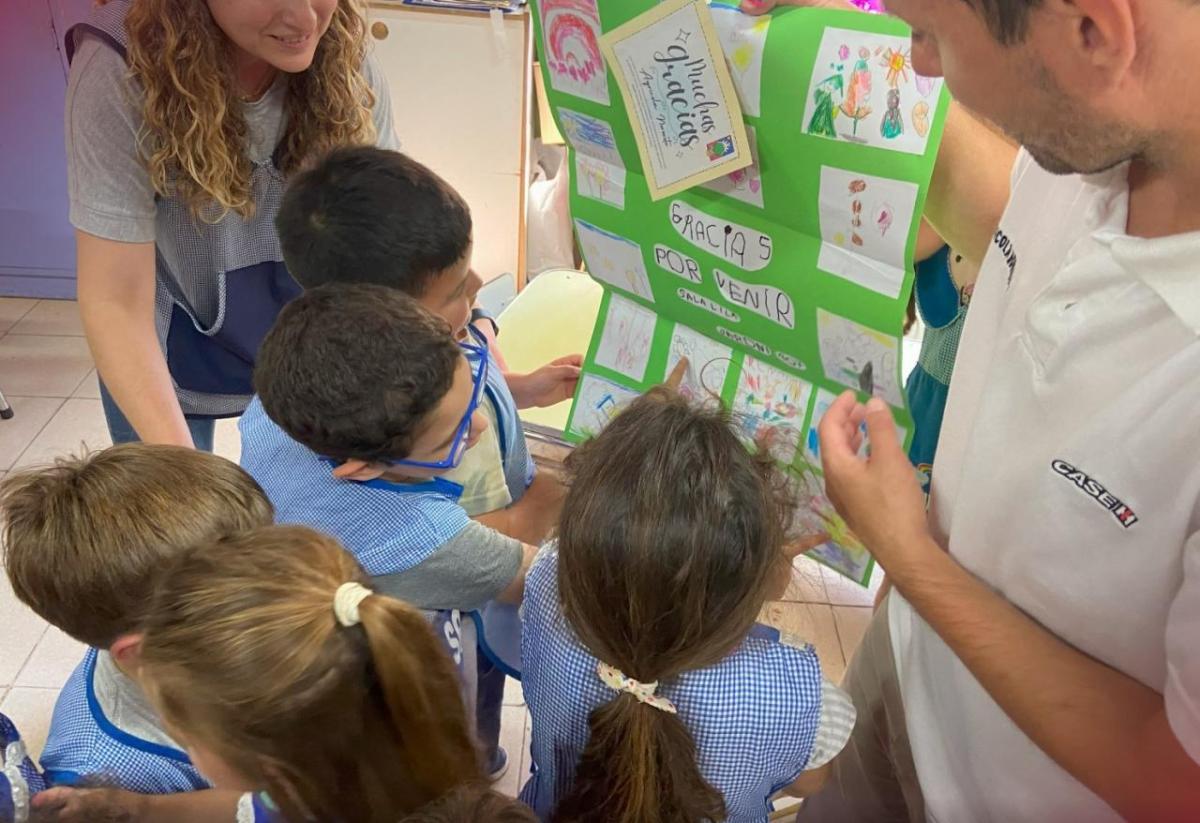 A group of children displaying their drawings to two adults