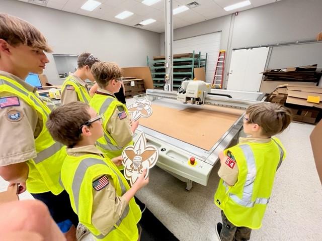 Children wearing hi-vis vests inside a manufacturing facility 