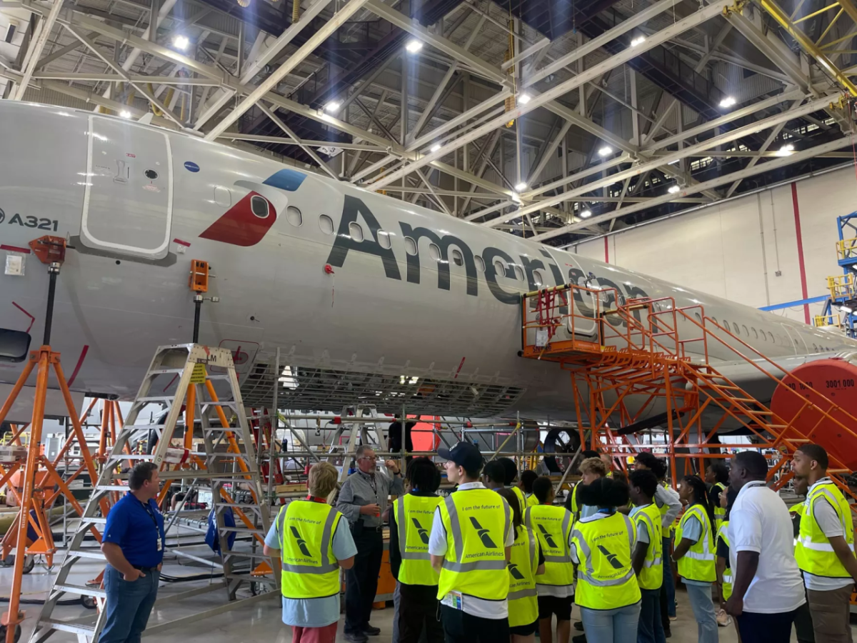 People in high visibility vests standing next to an American Airlines jet inside a hangar