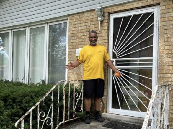 Derek shown in front of his family home.