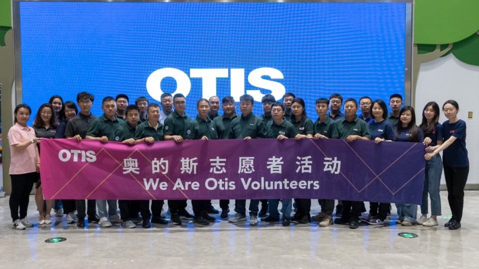 Otis China volunteer tutors holding banner