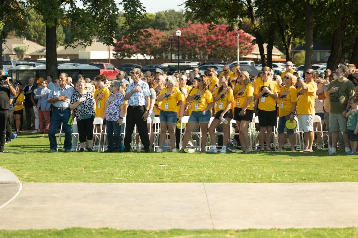 A crowd of people showing their respect by putting their right hand over their heart